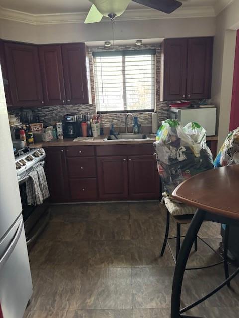 kitchen with range with gas cooktop, a sink, ornamental molding, a ceiling fan, and backsplash