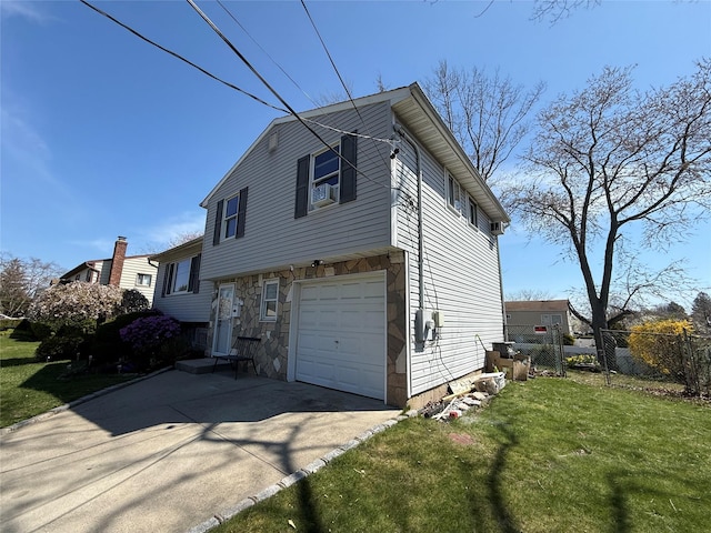 view of side of property featuring fence, a yard, an attached garage, driveway, and stone siding