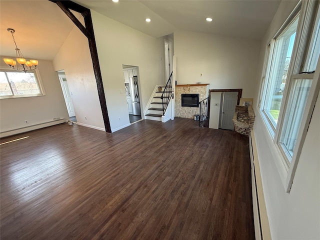 unfurnished living room featuring a glass covered fireplace, vaulted ceiling, a notable chandelier, and dark wood-style flooring