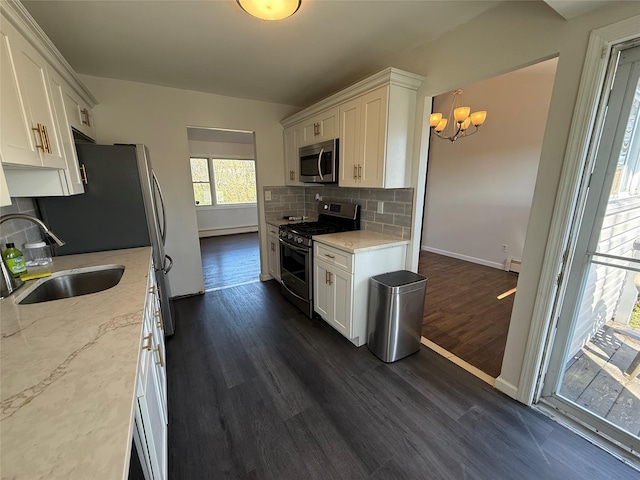kitchen featuring a sink, an inviting chandelier, backsplash, appliances with stainless steel finishes, and dark wood-type flooring