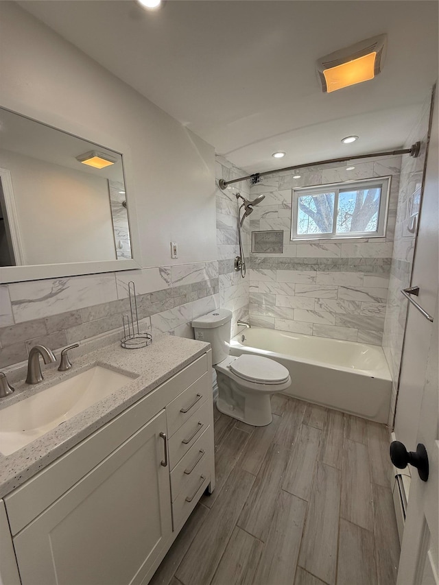 bathroom with wood finished floors, vanity,  shower combination, tile walls, and toilet