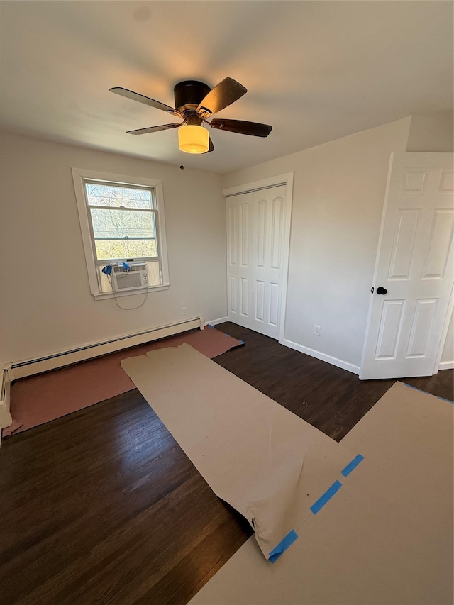 unfurnished bedroom featuring a baseboard radiator, a closet, cooling unit, baseboards, and dark wood-style floors