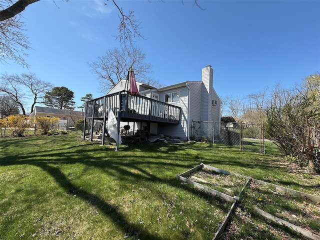 back of property featuring a lawn, a wooden deck, a garden, and stairs