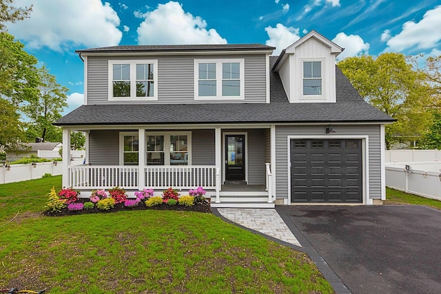 view of front of home with covered porch, asphalt driveway, a garage, and a shingled roof