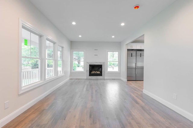 unfurnished living room featuring baseboards, wood finished floors, a premium fireplace, and recessed lighting
