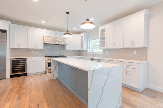 kitchen with beverage cooler, appliances with stainless steel finishes, under cabinet range hood, white cabinets, and light wood-style floors