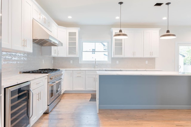 kitchen featuring wine cooler, high end stainless steel range oven, under cabinet range hood, light wood-type flooring, and recessed lighting