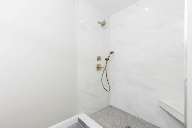 full bath with a tile shower and baseboards