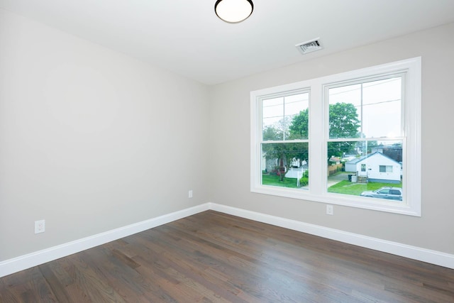 spare room featuring baseboards and dark wood-type flooring