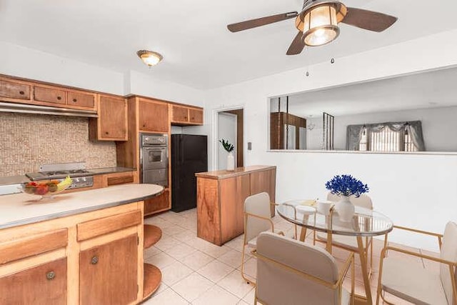 3317 Gunther Ave, Bronx, NY 10469 - kitchen with under cabinet range hood, decorative backsplash, black appliances, brown cabinetry, and ceiling fan