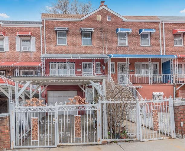 3317 Gunther Ave, Bronx, NY 10469 - townhome / multi-family property with a fenced front yard, brick siding, and a garage