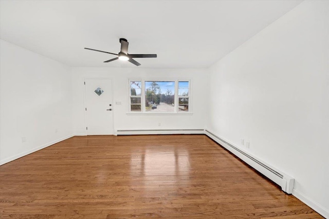 spare room featuring baseboards, ceiling fan, wood finished floors, and a baseboard heating unit