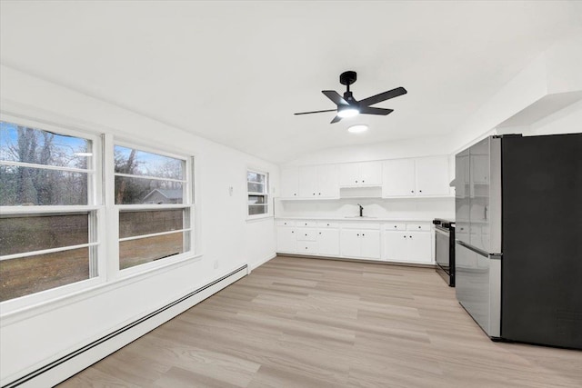 kitchen with a sink, freestanding refrigerator, white cabinetry, a baseboard radiator, and stove