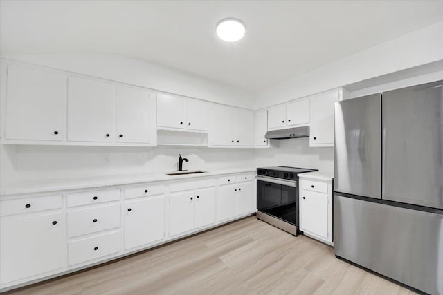 kitchen featuring light countertops, under cabinet range hood, a sink, range with electric stovetop, and freestanding refrigerator