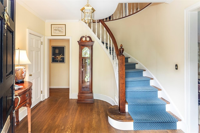 foyer featuring an inviting chandelier, stairs, baseboards, wood finished floors, and ornamental molding
