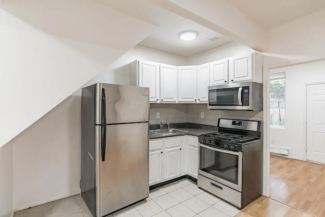 2263 Ryer Ave, Bronx, NY 10457 - kitchen featuring decorative backsplash, a sink, a baseboard radiator, white cabinets, and appliances with stainless steel finishes