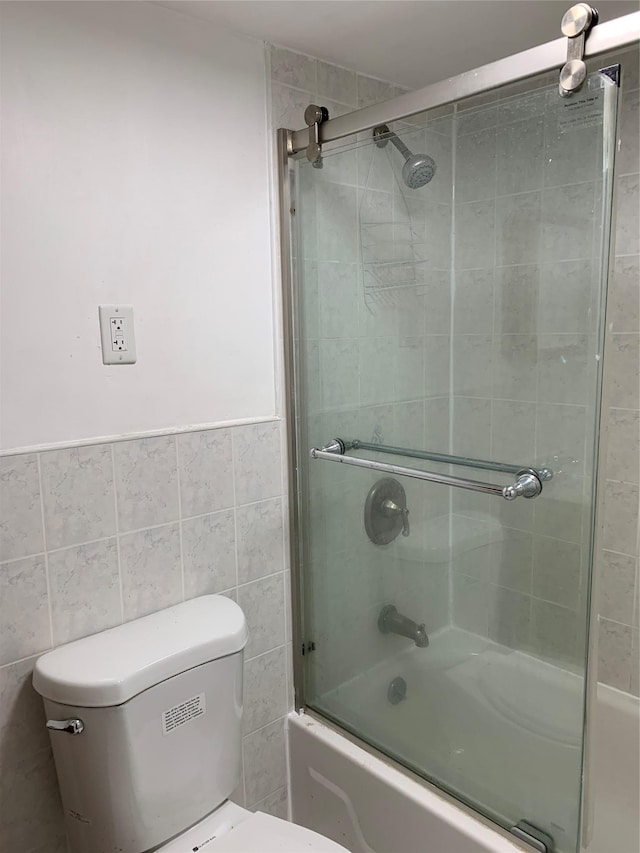 2263 Ryer Ave, Bronx, NY 10457 - full bathroom with combined bath / shower with glass door, toilet, tile walls, and a wainscoted wall