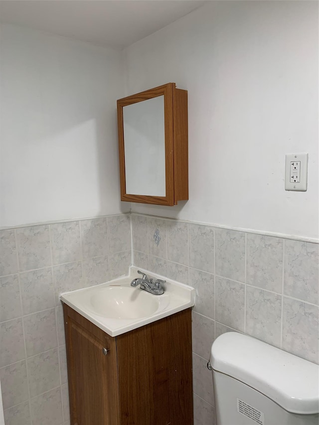 2263 Ryer Ave, Bronx, NY 10457 - bathroom with toilet, vanity, a wainscoted wall, and tile walls