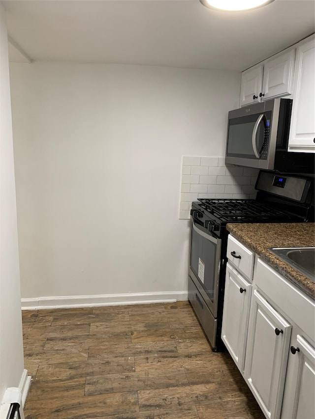2263 Ryer Ave, Bronx, NY 10457 - kitchen with decorative backsplash, dark countertops, appliances with stainless steel finishes, white cabinetry, and dark wood-style floors