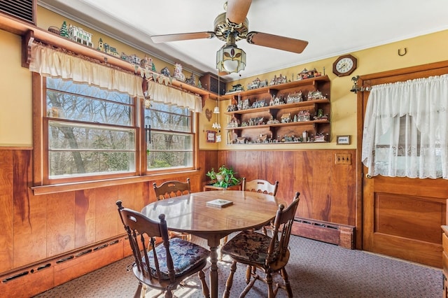 495 Knollwood Ln, Mattituck, NY 11952 - dining area with baseboard heating, wood walls, a ceiling fan, and a wainscoted wall