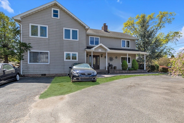 580 Foxhurst Rd, Baldwin, NY 11510 - view of front facade featuring a chimney, a porch, crawl space, and a shingled roof
