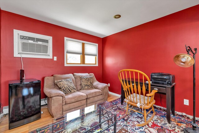 580 Foxhurst Rd, Baldwin, NY 11510 - living area featuring wood finished floors, an AC wall unit, baseboard heating, and baseboards