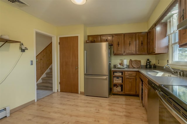 kitchen featuring a sink, light wood finished floors, brown cabinetry, stainless steel appliances, and visible vents