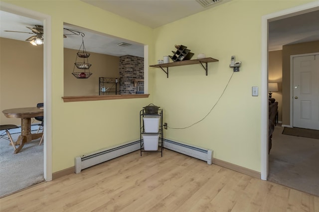 interior space featuring a baseboard radiator, wood finished floors, baseboards, and a ceiling fan