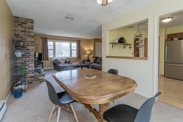 dining room featuring baseboard heating, baseboards, light colored carpet, and visible vents