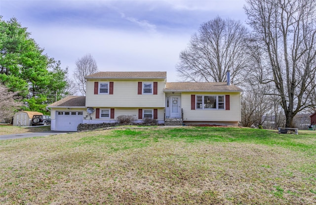 split level home with aphalt driveway, a storage shed, an attached garage, a front yard, and an outdoor structure