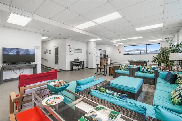 living room featuring finished concrete flooring, a baseboard heating unit, and a drop ceiling
