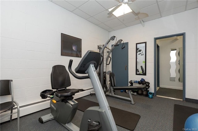workout room with a baseboard heating unit, ceiling fan, and a drop ceiling