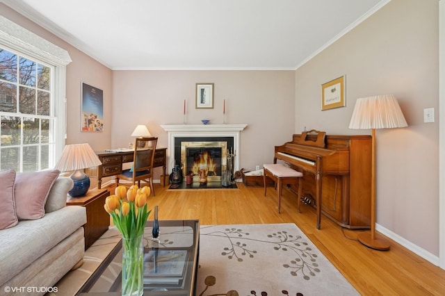 living room featuring a tiled fireplace, baseboards, wood finished floors, and crown molding