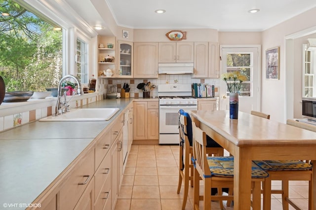 kitchen featuring white gas range oven, tasteful backsplash, a sink, light brown cabinets, and under cabinet range hood