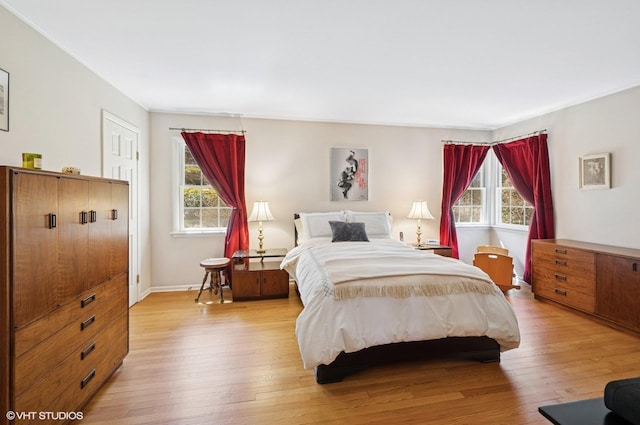 bedroom featuring light wood finished floors, multiple windows, and baseboards