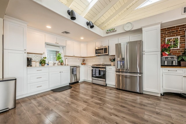 200 Block Ln, Island Park, NY 11558 - kitchen featuring appliances with stainless steel finishes, white cabinetry, backsplash, wood finished floors, and wood ceiling