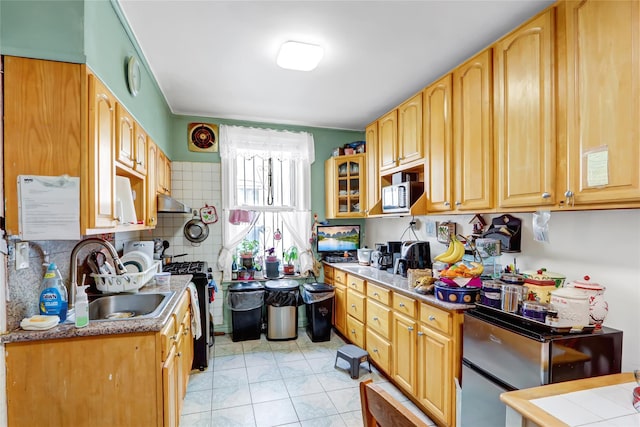 kitchen featuring light countertops, a sink, gas range, and glass insert cabinets