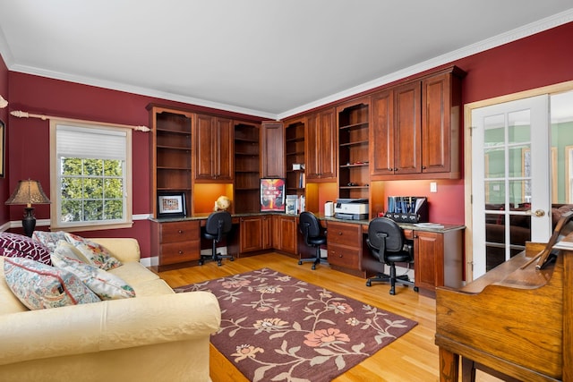 office with ornamental molding, light wood finished floors, and built in study area