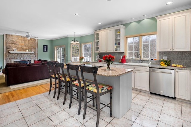kitchen featuring stainless steel dishwasher, ornamental molding, plenty of natural light, and a sink