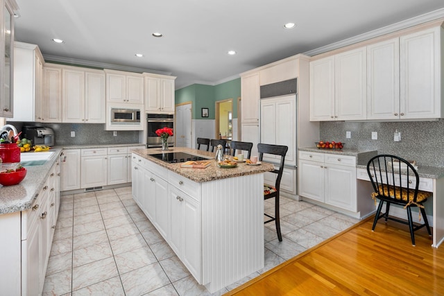 kitchen with a kitchen breakfast bar, a kitchen island with sink, backsplash, appliances with stainless steel finishes, and ornamental molding