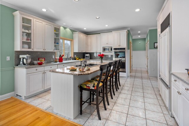 kitchen featuring decorative backsplash, a breakfast bar, recessed lighting, a center island, and stainless steel appliances