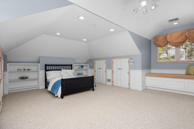 bedroom with carpet floors, visible vents, wainscoting, and lofted ceiling