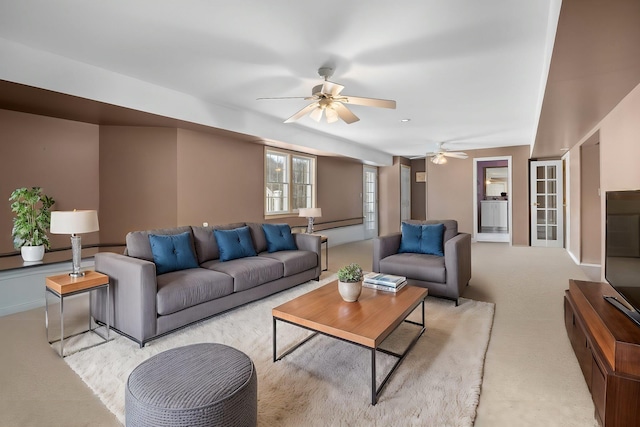living area with baseboards, light carpet, and a ceiling fan