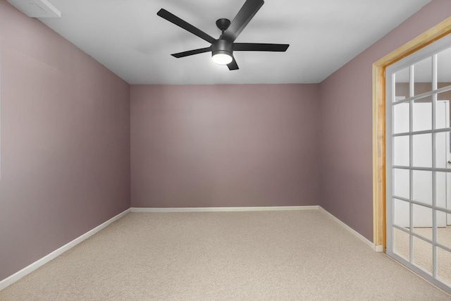 carpeted spare room with a ceiling fan and baseboards