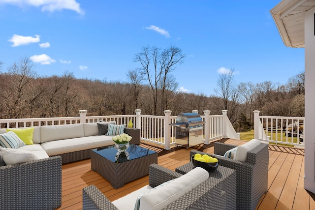 deck featuring a view of trees, an outdoor living space, and a grill