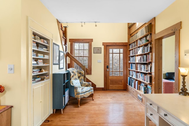 sitting room with light wood-style flooring, baseboards, rail lighting, and built in shelves