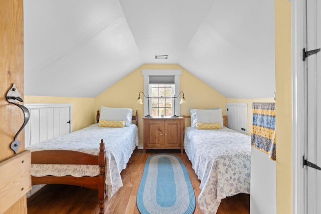 bedroom with lofted ceiling, wood finished floors, and visible vents