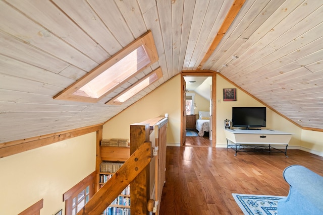 additional living space with baseboards, vaulted ceiling with skylight, hardwood / wood-style floors, and wood ceiling