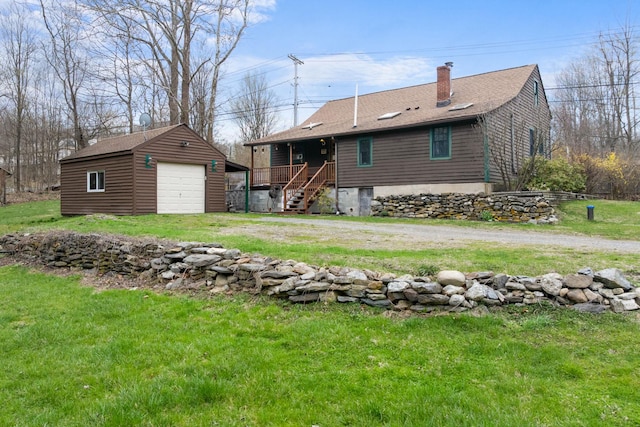 back of house featuring a chimney, a lawn, an outdoor structure, a garage, and roof with shingles