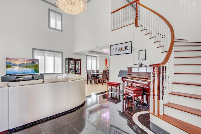living room featuring granite finish floor, a high ceiling, stairway, and a chandelier